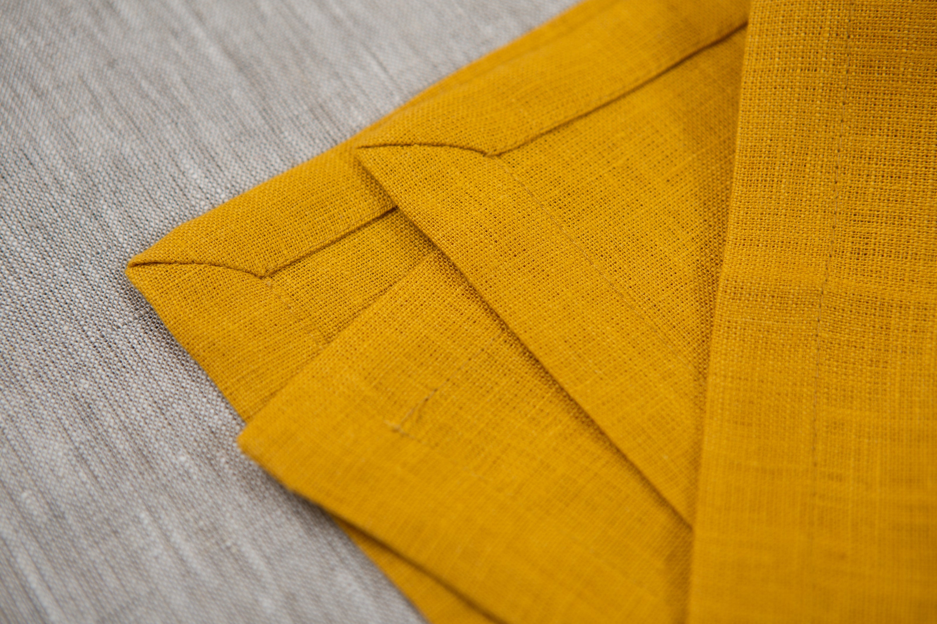 Warm mustard organic linen napkins with mitered corners – the perfect way to create a cozy, eco-conscious dining atmosphere.