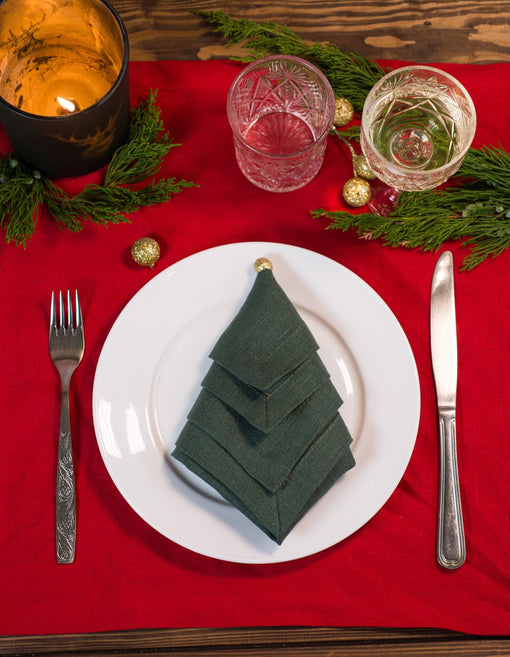 Basil green linen napkin folded into a Christmas tree on a festive table