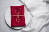 Wine red linen napkin with jute twine on a white plate – autumn and Halloween table decor