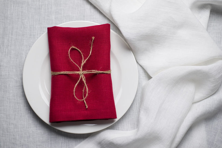 Wine red linen napkin with jute twine on a white plate – autumn and Halloween table decor