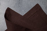 Close-up of cacao brown stonewashed linen corner on concrete – natural linen texture