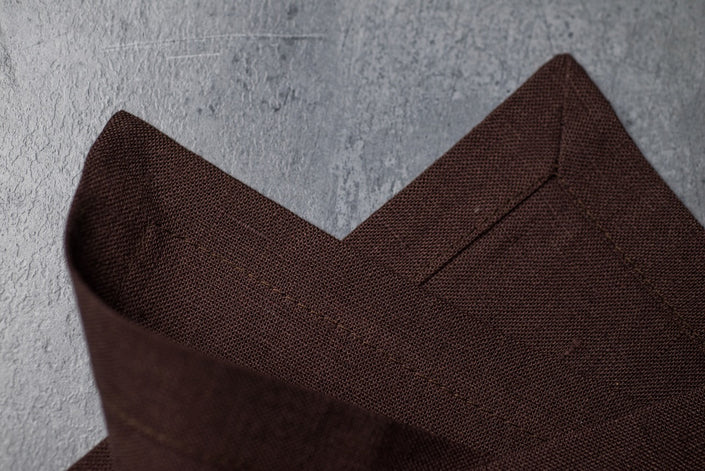Close-up of cacao brown stonewashed linen corner on concrete – natural linen texture