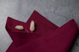 Folded plum linen napkins on concrete with dried bunny tail grass