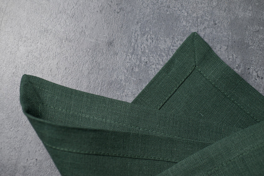Close-up of Basil green linen fabric showing its woven texture and neatly stitched hem