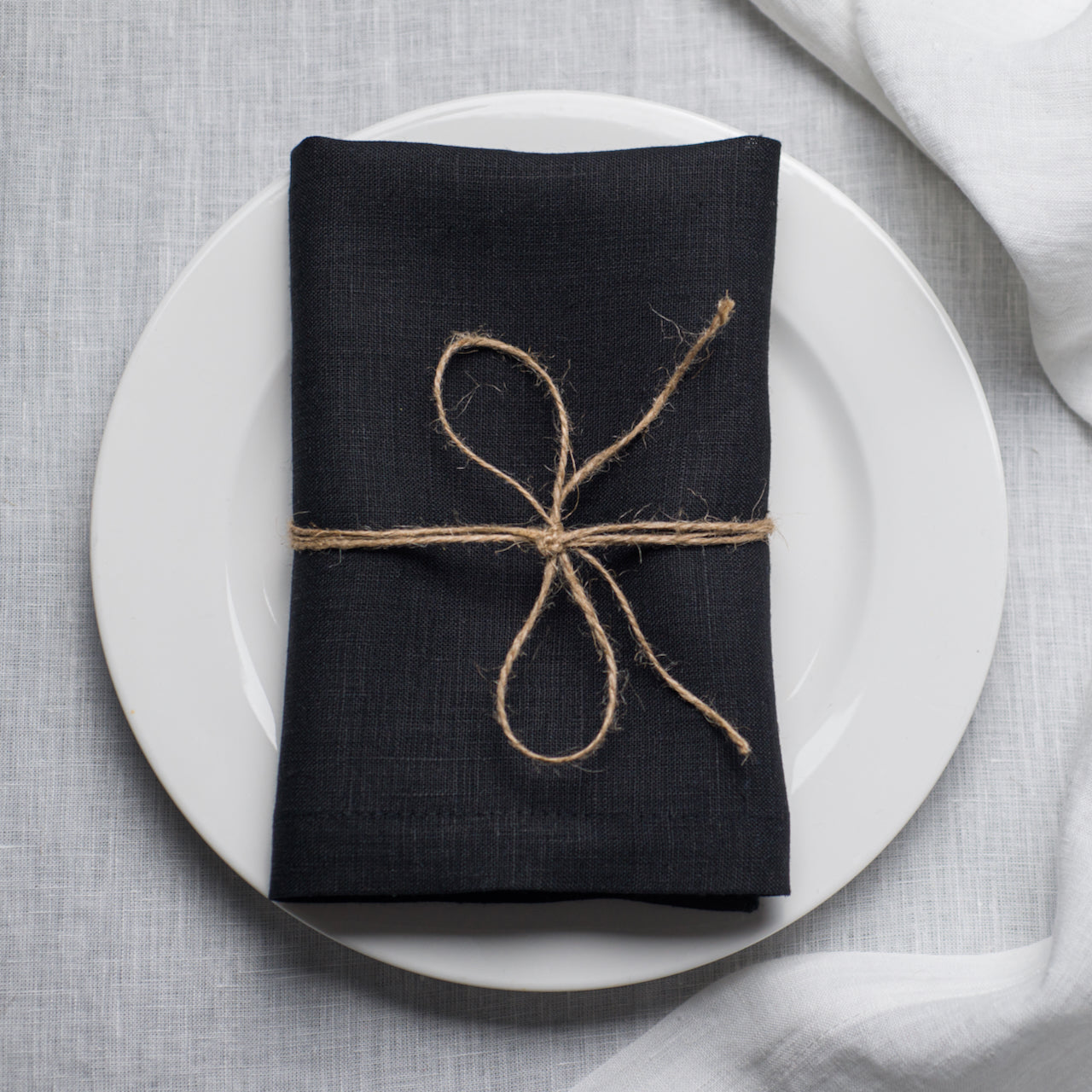 Black linen napkin with mitered corners on table setting, organic flax cloth napkin for elegant dining and modern home decor