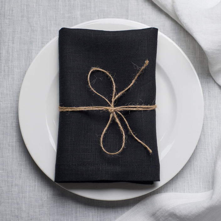 Black linen napkin with mitered corners on table setting, organic flax cloth napkin for elegant dining and modern home decor