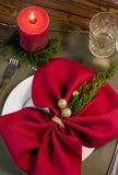 Close-up of a classic red linen napkin bow with gold berries and greenery on a Christmas place setting