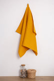 Mustard linen tea towel with a hanging loop on a wall hook