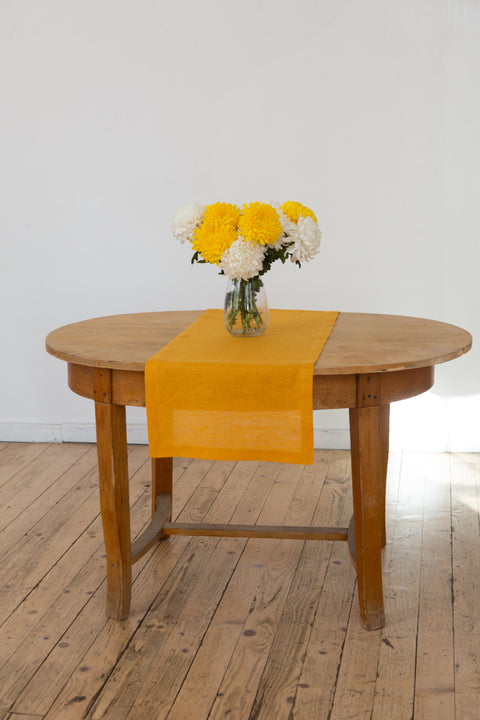 Mustard linen table runner with a vase of yellow and white chrysanthemums