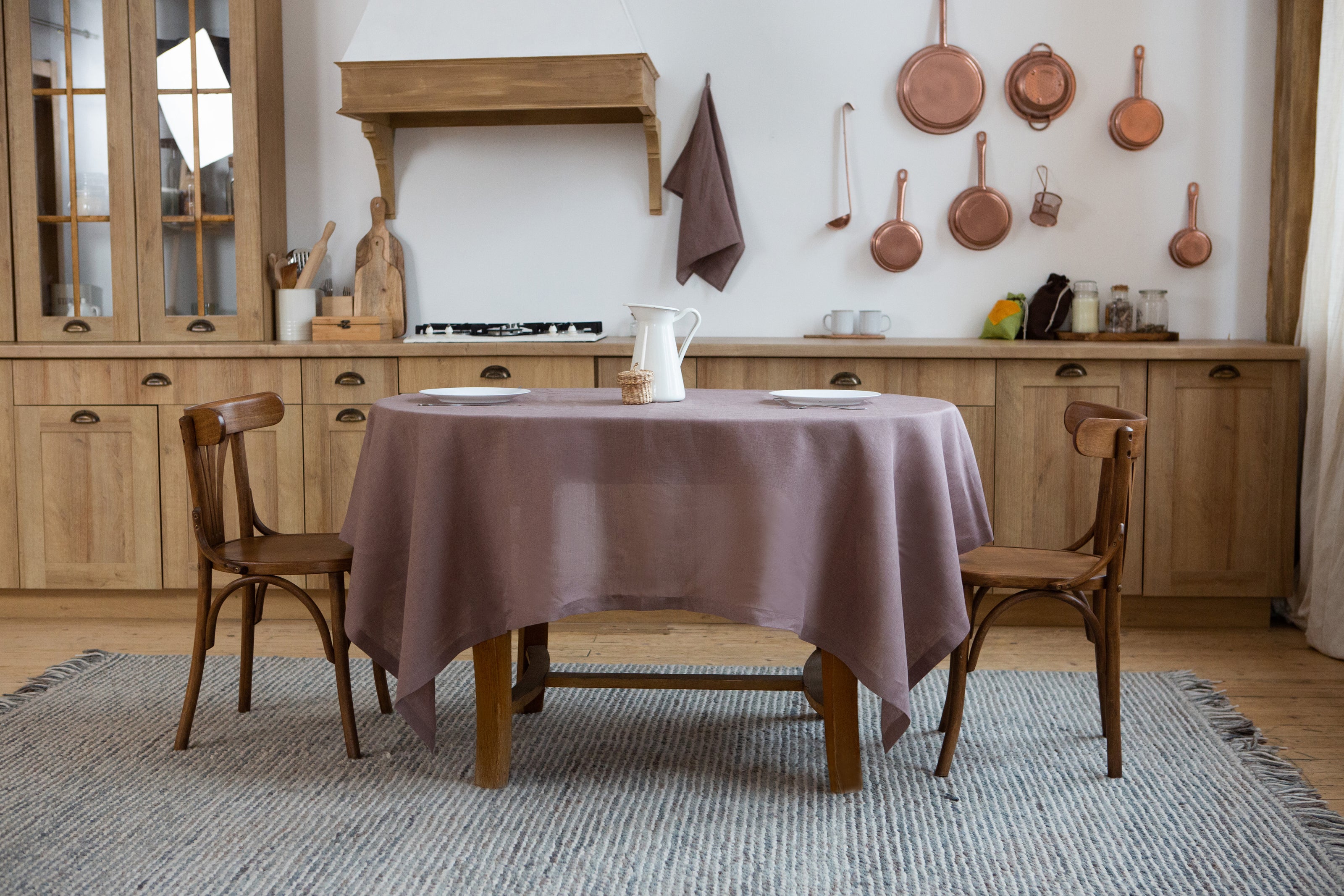 Cozy kitchen dining area with wooden table, chairs, and limed oak linen tablecloth.