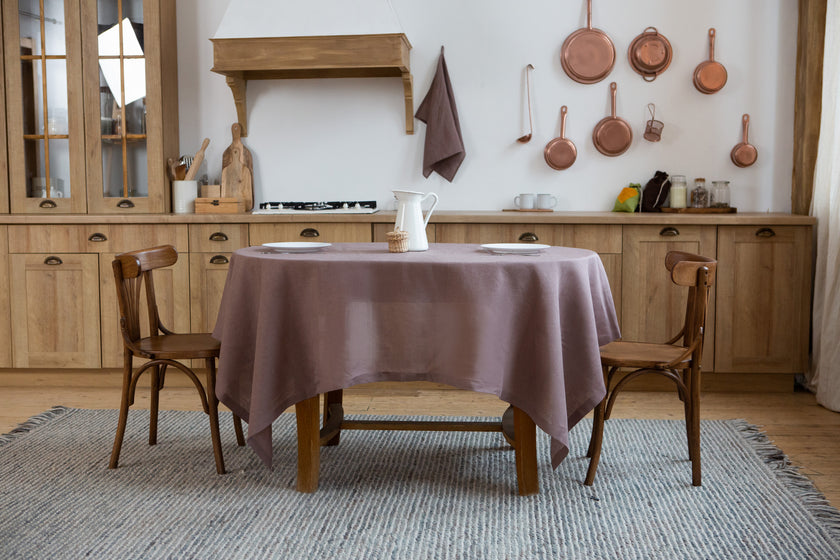 Cozy kitchen dining area with wooden table, chairs, and limed oak linen tablecloth.