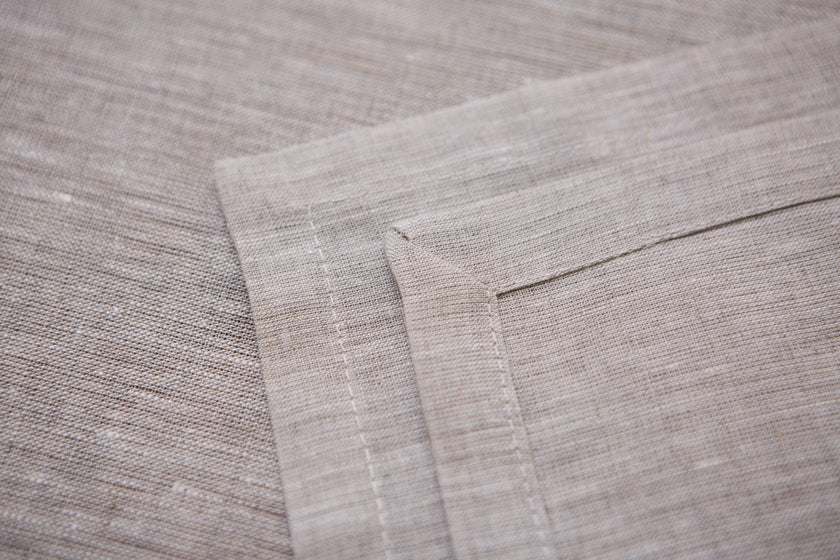 Close-up of Natural beige linen fabric showing its woven texture and mitered hem