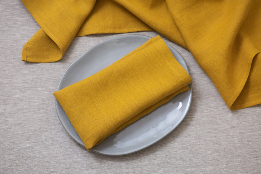 Bright mustard linen napkins with mitered corners. Ideal for adding warmth and charm to your dining experience.
