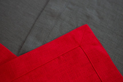 Close-up of the neatly hemmed corner of a red linen table runner