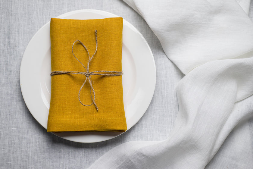 Easter yellow organic linen napkin styled with a bow on a festive spring table. Made from 100% natural linen, it adds a fresh and joyful touch to Easter brunch decor. Sustainable and reusable table textile for seasonal celebrations.