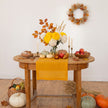 Mustard linen table runner on a wooden table with pumpkins, candles and yellow chrysanthemums – Thanksgiving table decor – CoolLinen