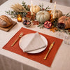 Terracotta linen placemat with a natural linen napkin, white plate and gold cutlery on a Thanksgiving table with pumpkins and candles – CoolLinen