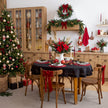 Black round linen tablecloth with red placemats, light linen napkins and candles in a Christmas table setting