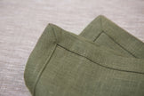 Olive green linen napkins with mitered corners, close-up