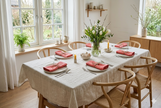 Dining room with a table set for a meal with organic linen napkins in salmon color, featuring a vase of flowers and place settings. Easter dinner, romantic spring table styling. 