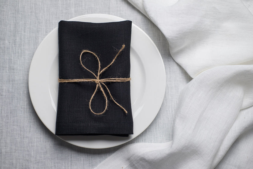 Black linen napkin tied with jute twine on a white plate