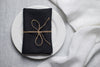 Black linen napkin tied with jute twine on a white plate