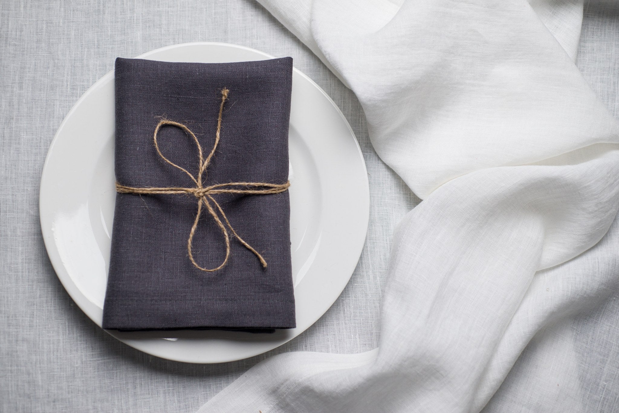 Slate linen napkin tied with jute twine on a white plate