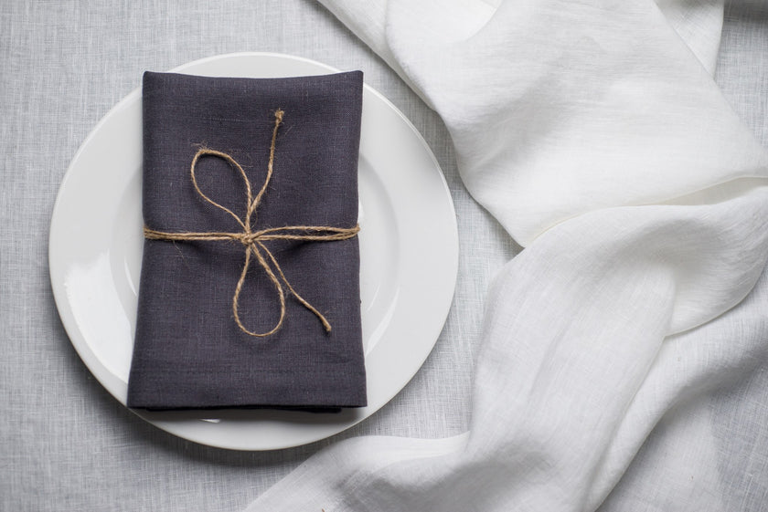 Slate linen napkin tied with jute twine on a white plate