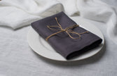 Slate linen napkin tied with jute twine on a white plate, side view