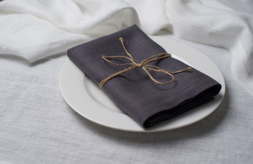 Slate linen napkin tied with jute twine on a white plate, side view
