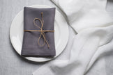 Grey linen napkin tied with jute twine on a white plate