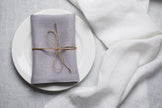 Light Grey linen napkin tied with jute twine on a white plate