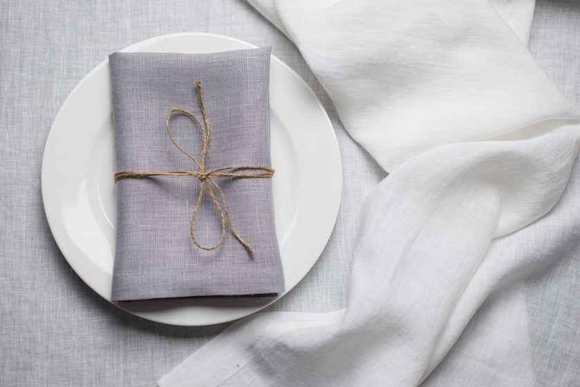 Light Grey linen napkin tied with jute twine on a white plate