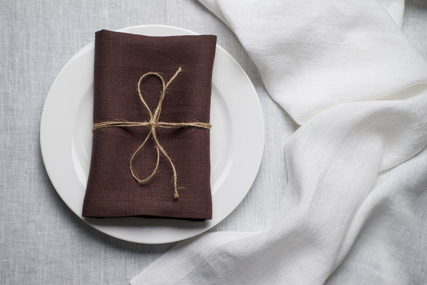 Cacao linen napkin tied with jute twine on a white plate