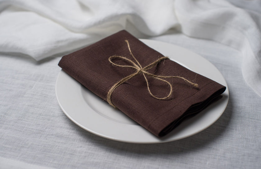 Cacao linen napkin tied with jute twine on a white plate, side view