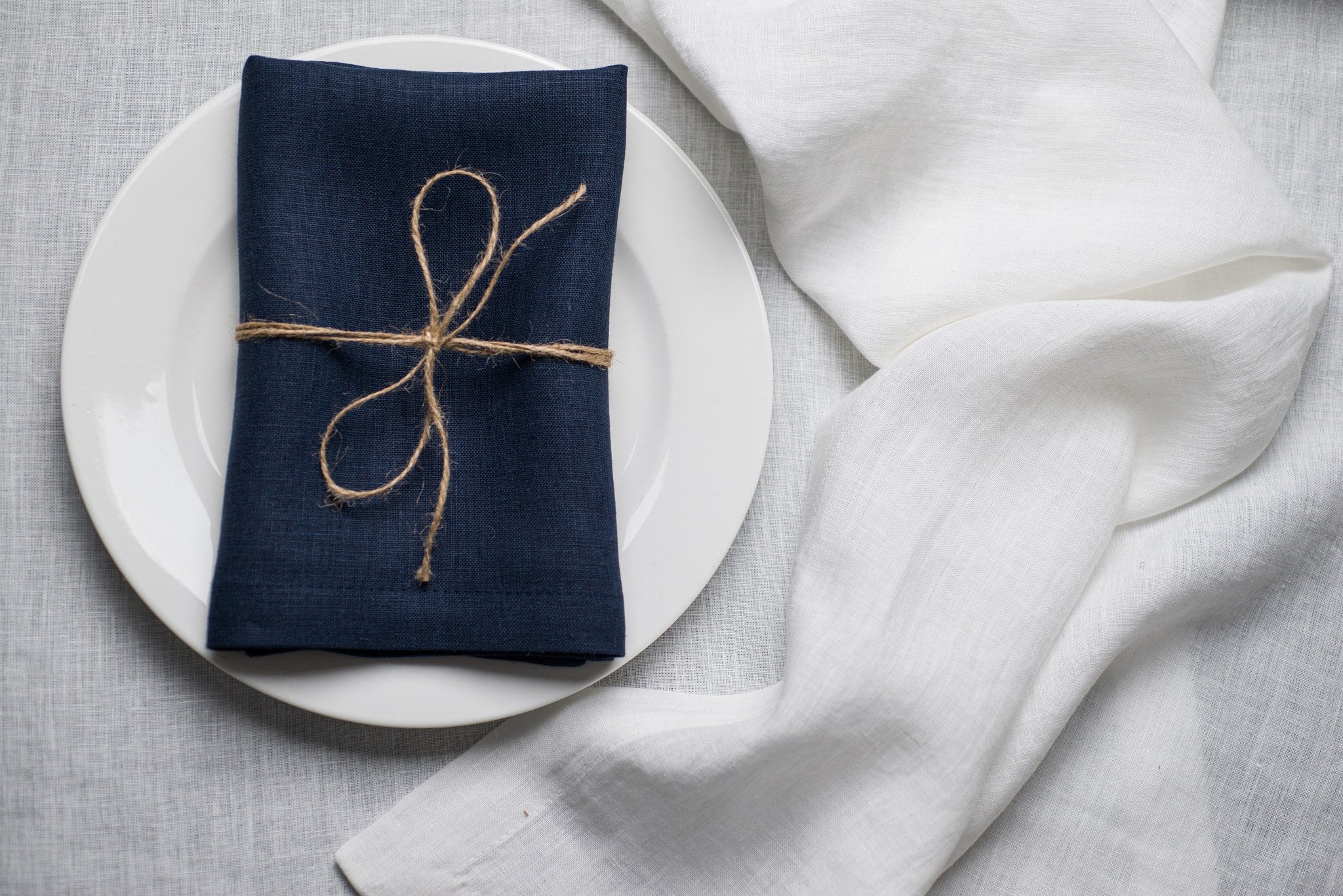 Old Navy linen napkin tied with jute twine on a white plate