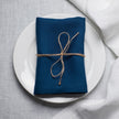 Blue linen napkin tied with jute twine on a white plate