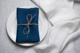 Blue linen napkin tied with jute twine on a white plate