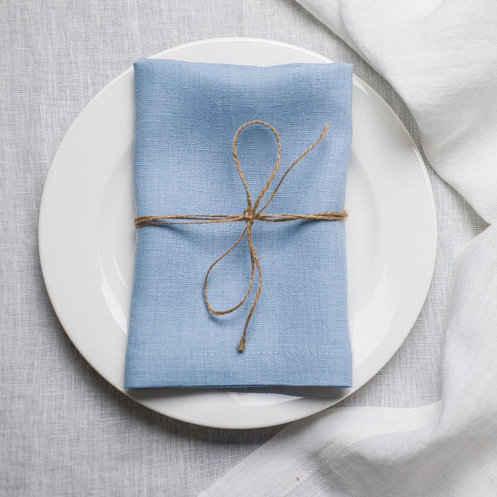 Sky linen napkin tied with jute twine on a white plate