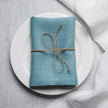 Teal linen napkin tied with jute twine on a white plate