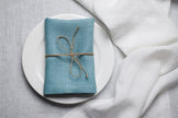 Teal linen napkin tied with jute twine on a white plate