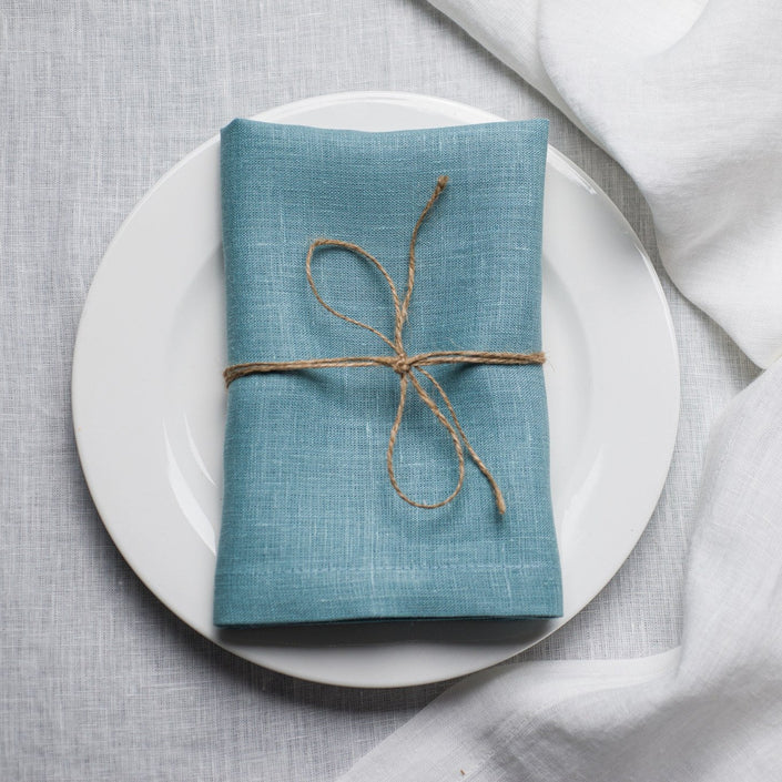 Teal linen napkin tied with jute twine on a white plate