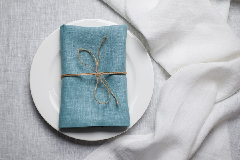 Teal linen napkin tied with jute twine on a white plate