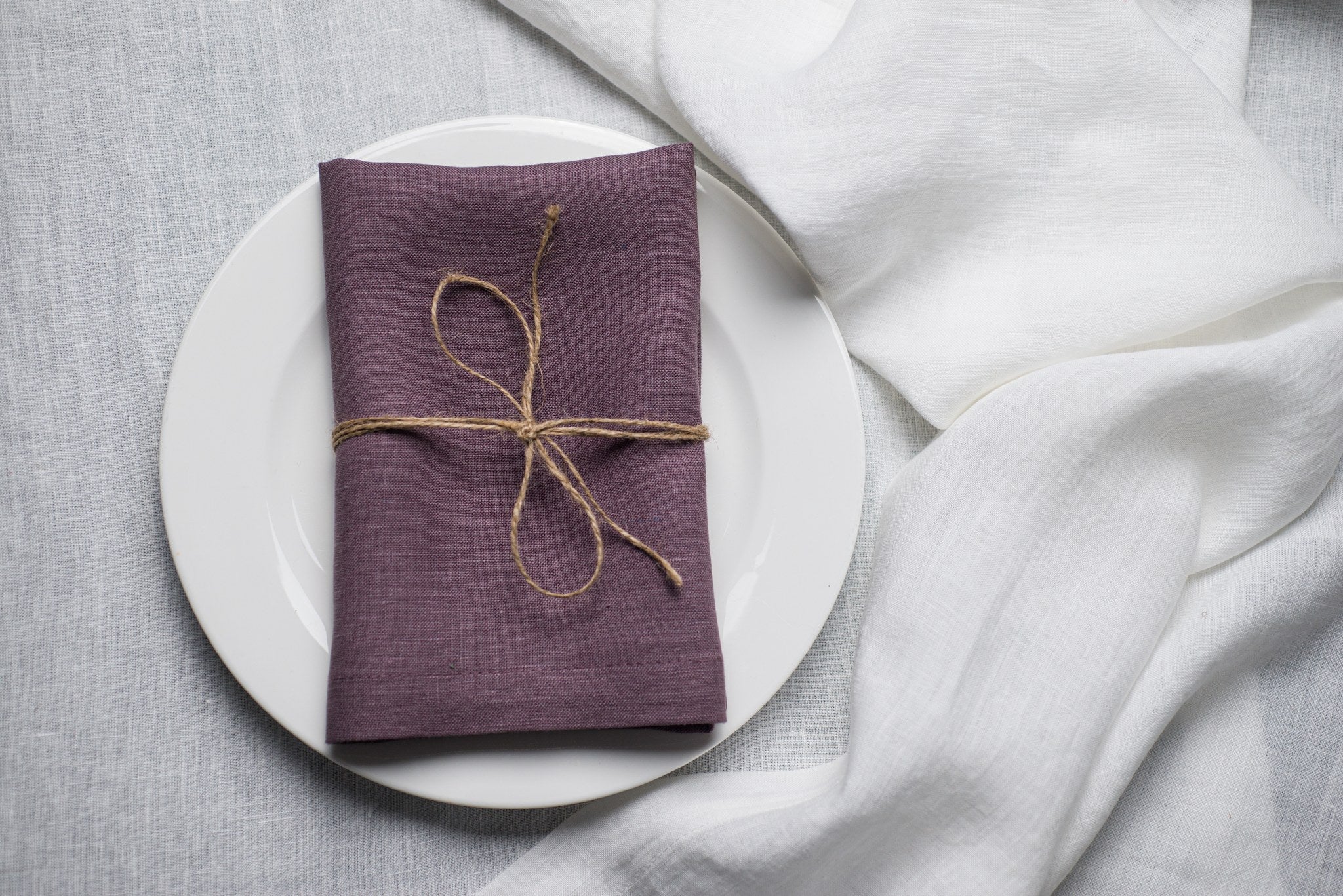 Fog linen napkin tied with jute twine on a white plate