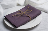 Fog linen napkin tied with jute twine on a white plate, side view