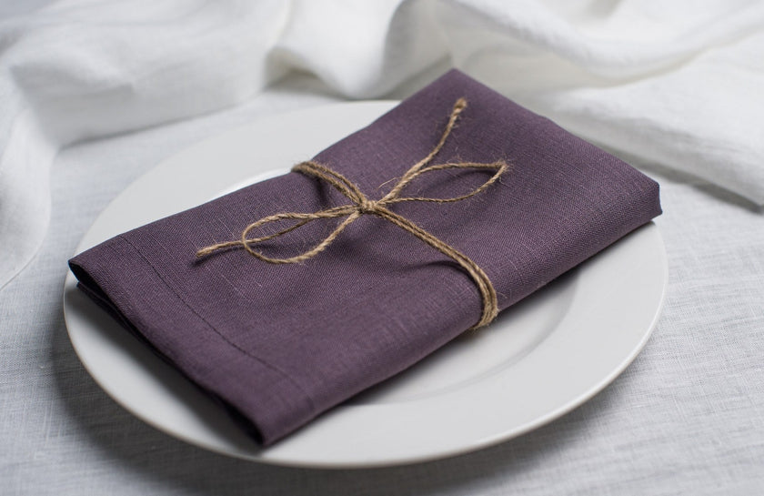 Fog linen napkin tied with jute twine on a white plate, side view