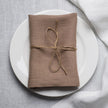 Oat linen napkin tied with jute twine on a white plate