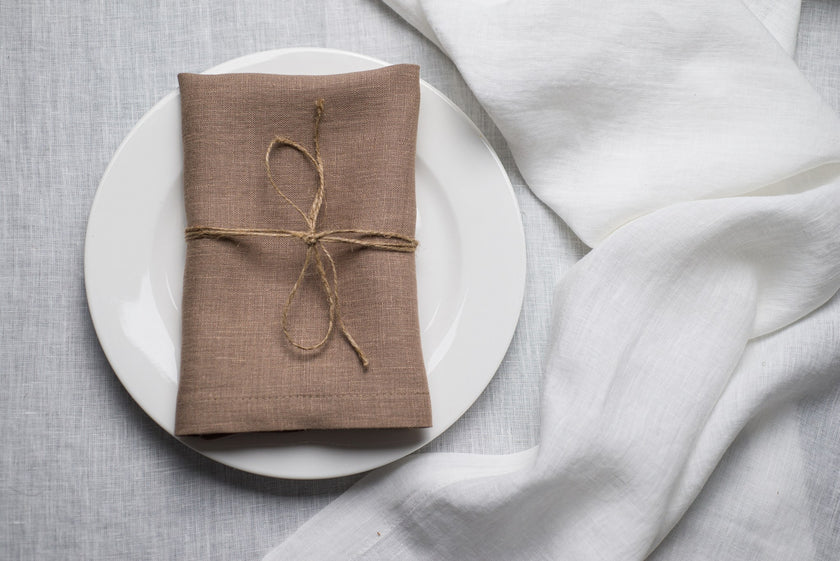 Oat linen napkin tied with jute twine on a white plate