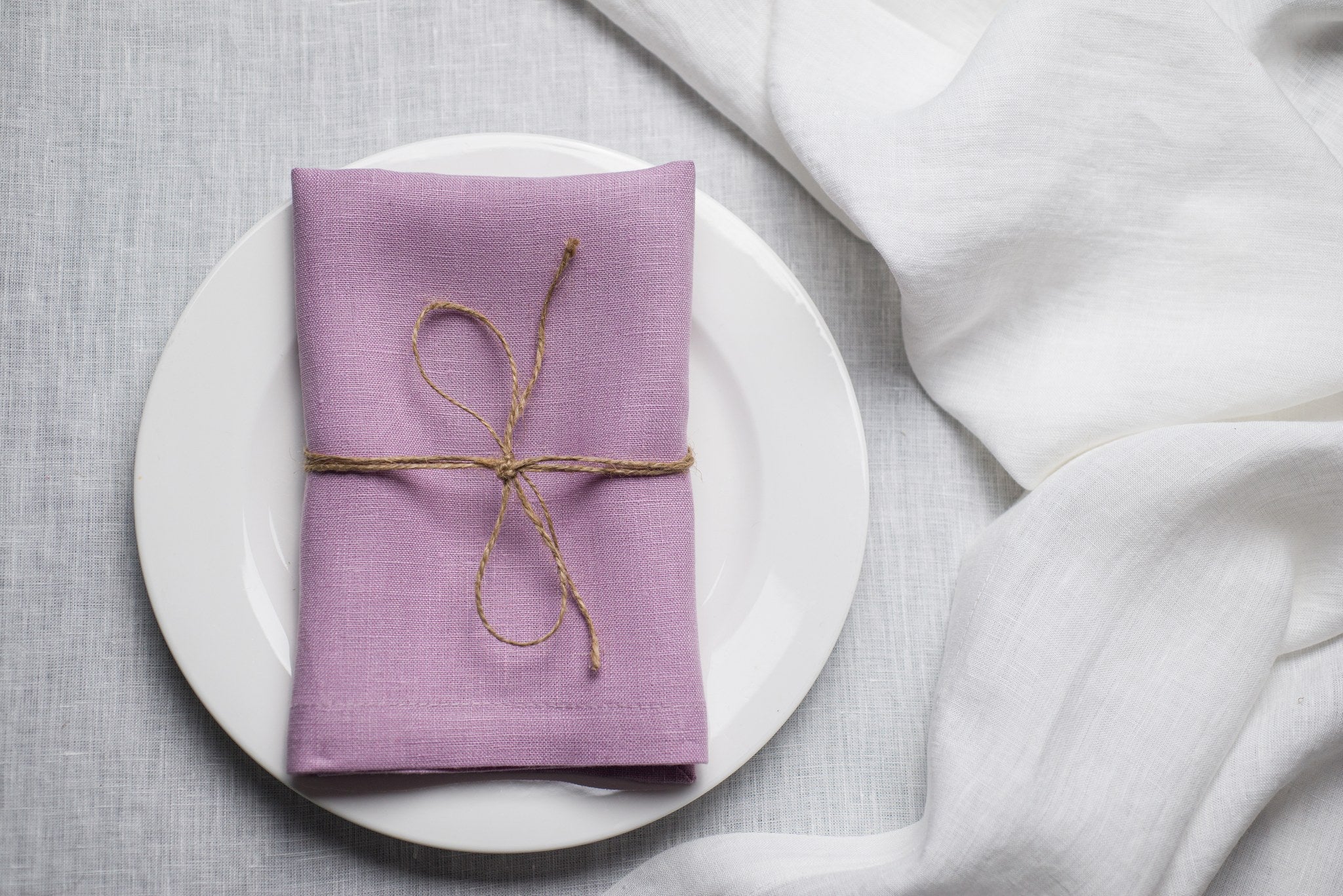 Lavender linen napkin tied with jute twine on a white plate