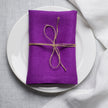 Violet linen napkin tied with jute twine on a white plate